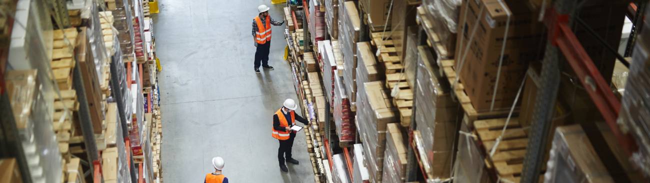 Workers managing inventory inside a warehouse aisle