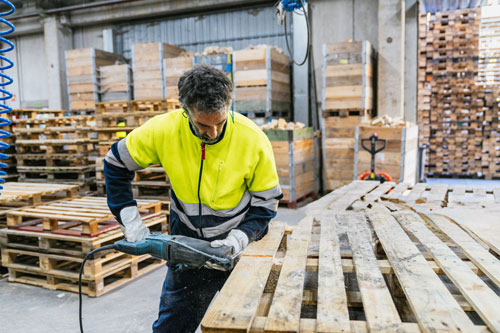 Worker cutting wood for pallet repair